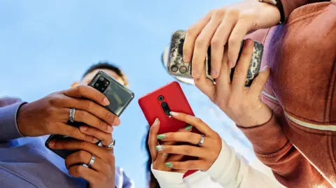 Getty Images Stock representation  of 3  young radical   utilizing their smartphones