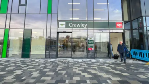 Getty Images the newly redeveloped Crawley train station, with grey paving on the concourse and a large sign over glass sliding doors.