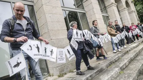 People holding a long banner made of sheets of paper