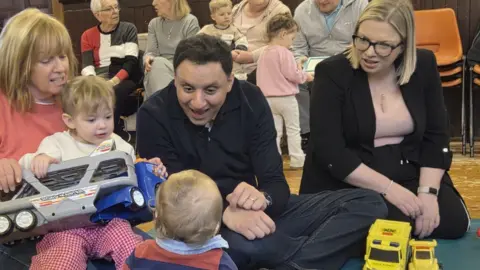 PA Media Anas Sarwar, who has short black hair, plays with children at a nursery 