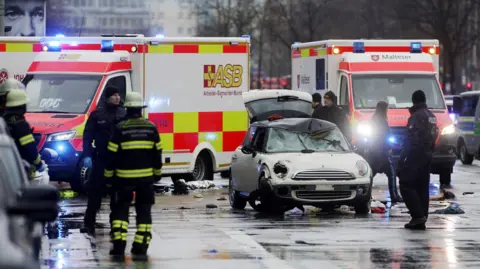 Getty Images Police and emergency services stand near a damaged car that drove into demonstrators marching in Munich, Germany on 13 February 2025