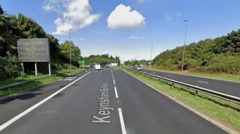 A streetview image of the road, which is a dual carriageway approaching a large roundabout. 