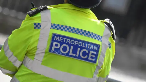 The back of a Metropolitan Police officer wearing a hi-vis jacket.