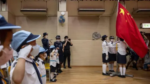 Getty Images Students salute while watching the flag-raising ceremony to commemorate the 72nd anniversary of the establishment of the People's Republic of China at a school in Hong Kong