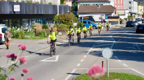 bbc Eight cyclists on a road in the town centre approaching a roundabout