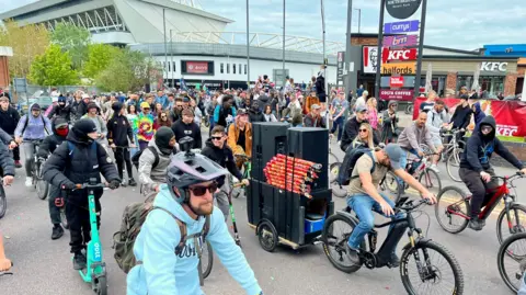 Steve Mellen/BBC Hundreds of cyclists set off at the start of the Bristol Drum & Bass Bike Ride, with Ashton Gate Stadium in the background