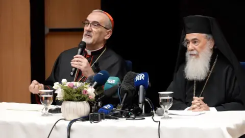 Holy Family Church Speaking in front of microphones on top of a white table the Latin Patriarch Cardinal Pierbattista Pizzaballa and Greek Orthodox Patriarch Theophilos III address reporters in Jerusalem on 22 July 2025