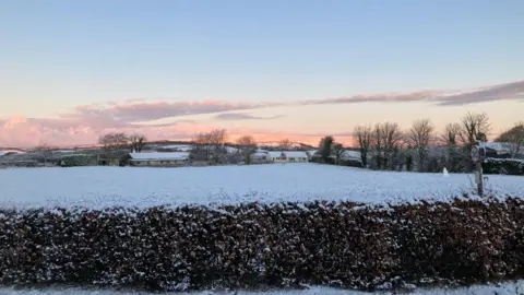 A field covered at snow with pink clouds above