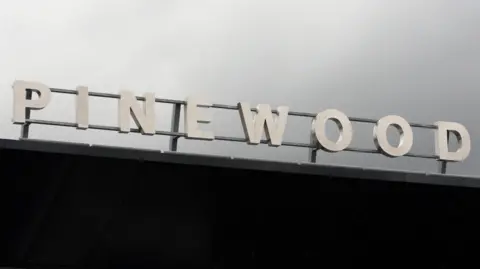 The Pinewood sign, on top of the studios building, on a grey and cloudy day.