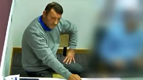 GMP Paul Quinn sat in a police interview room 