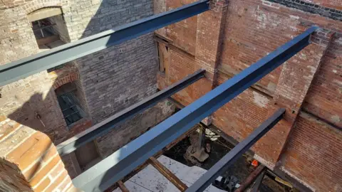 Daniel Mumby A building site showing steel beams between two red brick walls