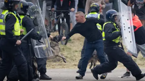 Getty Images A man being restrained by police, with a police dog biting his arm