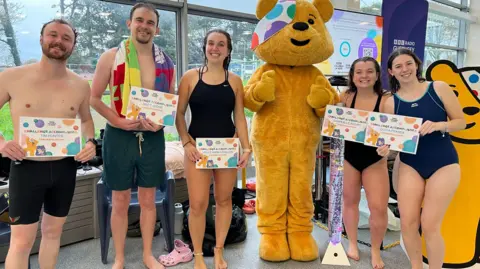 BBC Two male and three females in swimming gear and holding certificates with Children in Need's Pudsey.