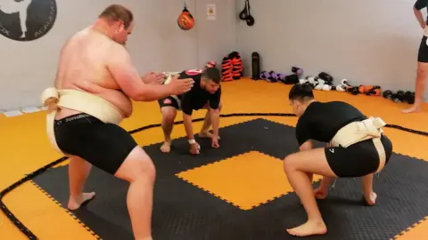 BARNSLEY SUMO CLUB Richard and another sumo wrestler at the club are squatting opposite each other in the ring.