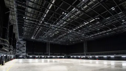 Sky Studios Elstree A huge room with a polished concrete floors, black walls and lighting rigs on the ceiling