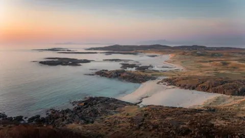 Jez Campbell Pastel sky of blue and orange over a blue sea and beach at Sanna, Ardnamurchan.