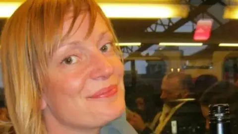 PA A woman with blonde hair, her face framed by a fringe, smiles at the camera
