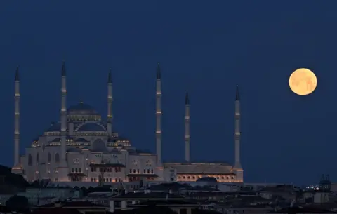 Getty Images The full moon rises behind the Grand Camlica Mosque in Istanbul, Turkey
