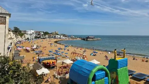 Top shot of crowds on a sandy beach in Broadstairs, Kent, with the sea in the background on a sunny day 