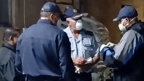 Three officers in face masks and uniform in discussion during a raid on a meth lab found at a farm in Limpopo province