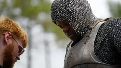 Courtesy of HBO and Creative Wales Aaron with man dressed as knight in armour facing each other
