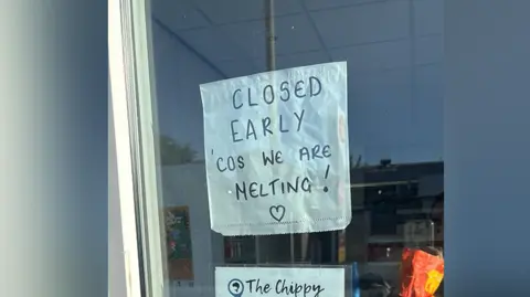 The front door of a closed fish and chip shop with a sign which reads 'closed early 'cos we are melting'.