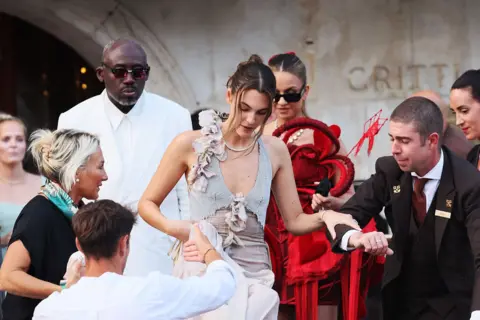 Getty Images Edward Enninful and Vittoria Ceretti in Venice, Italy, for the wedding of Jeff Bezos and Lauren Sanchez. Edward is wearing a bright white suit and Vittoria is wearing a pastel pink coloured gown. 