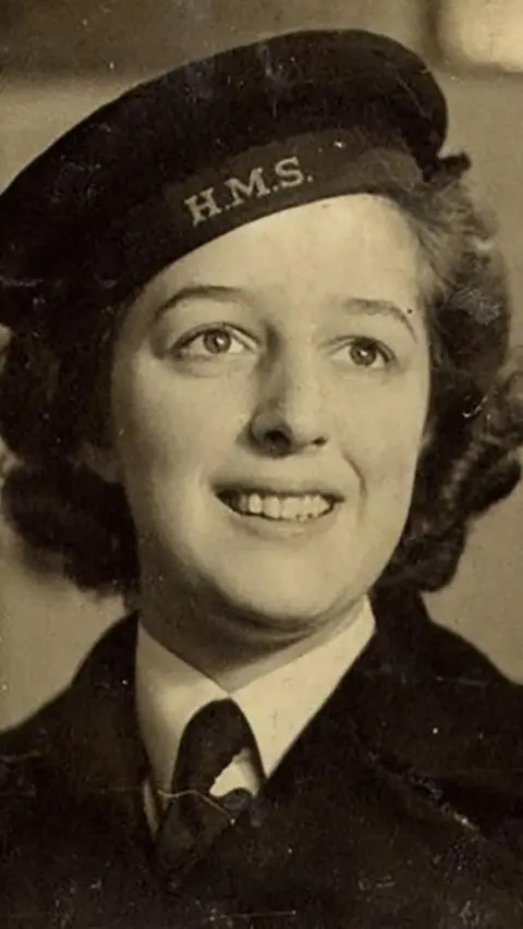 PA Black and white image of a young woman in uniform. She smiles and looks away from the camera.