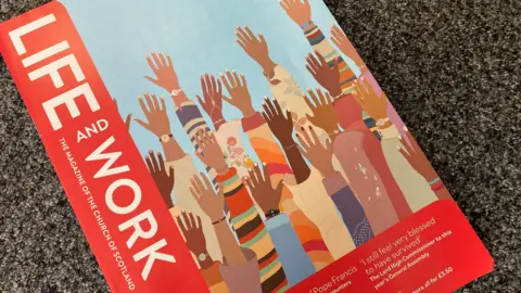 The magazine has a red margin down one side with the words: "Life and Work. The magazine of the Church of Scotland." The cover has a stylised image of raised hands against a blue background.