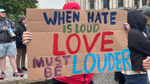 Sign in protest, 'When hate is hated, loud love should be enough'.