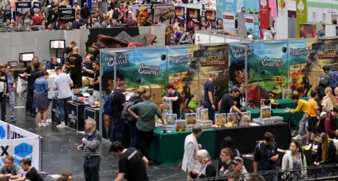 UK Games Expo A crowded hall with people walking between stalls and looking at trade stands