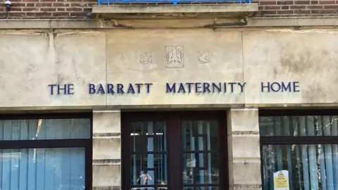 James Grant/BBC Stone-fronted building with large windows and door on the ground floor and "THE BARRATT MATERNITY HOME" in dark blue lettering on the first floor.