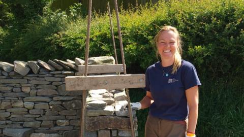 Waller Vicki Smith standing by dry stone wall