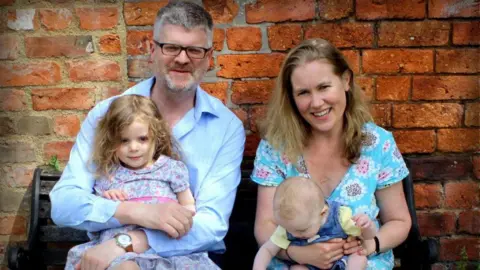 Handout A man and a woman holding two young children.