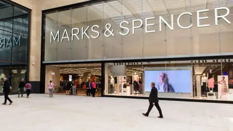 People walking in front of a Marks & Spencer store
