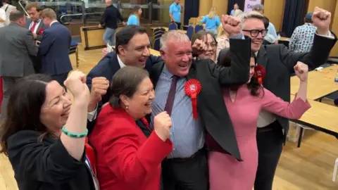 A crowd of people celebrate with their fists in the air 