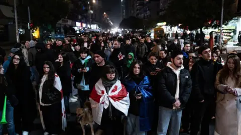 Jerome Gilles/NurPhoto Protesters walk through Batumi in the dark, clad in Georgian flags