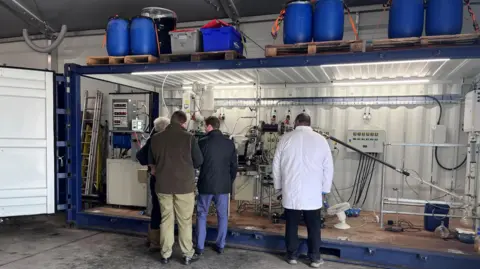 A team of workers operating the demonstrator 'cracker' within a shipping container