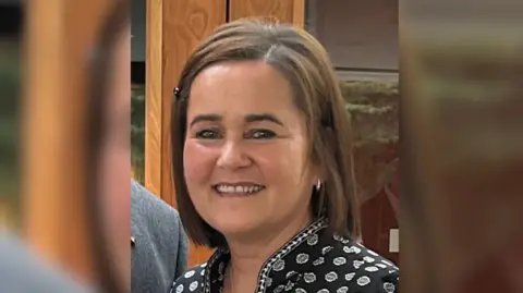 Ursula O'Hanlon Ursula O'Hanlon has shoulder length brown hair and is wearing a black printed top and makeup.