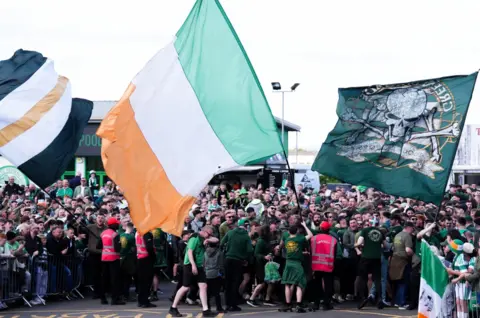 PA Media Celtic fans ahead of the William Hill Premiership match at Celtic Park, Glasgow. They wave an Irish flag and the flag of the Green Brigade which features a skull and cross bones. 