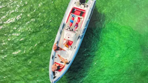 MAIB An aerial view of Peaky Blinder shows the RIB in bright green water. Four people are on board - the MAIB has blurred their heads to protect their identities.