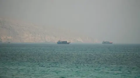 Two vessels are seen in the Strait of Hormuz, surrounded by rocky mountains, from Musandam, Oman