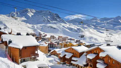 Getty Images View of snow-covered wooden buildings in Val Thorens, with snow-covered peaks in the background.