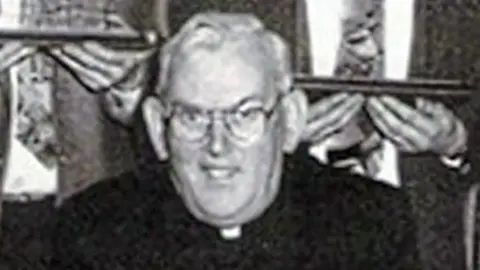 Pacemaker Black and white image of Fr Malachy Finegan. He has white hair and wearing glasses,