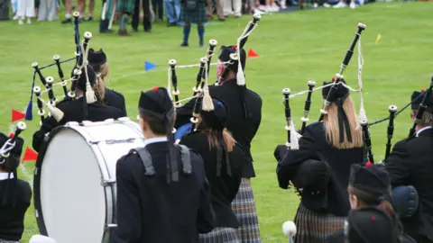 Getty Images Generic image of pipe band playing in a field with people observing