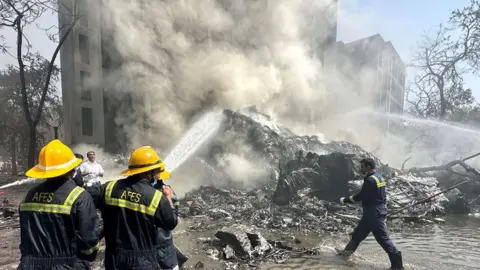Rescue team members work as smoke rises at the site where an Air India plane crashed in Ahmedabad, India, June 12, 2025.
