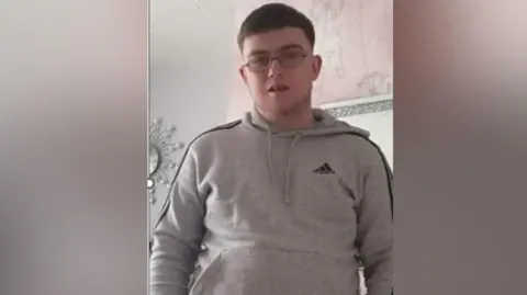 Daniel Ambler, a 23-year-old man with short dark hair, wearing spectacles and a grey hoodie.