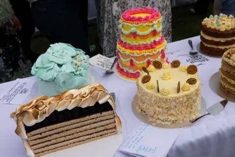 Jessica Hromas/BBC Four cakes on a table: one turquoise, one double-layered and multi-coloured (red, yellow, turquoise), one coconut-white chocolate and one dulce de leche