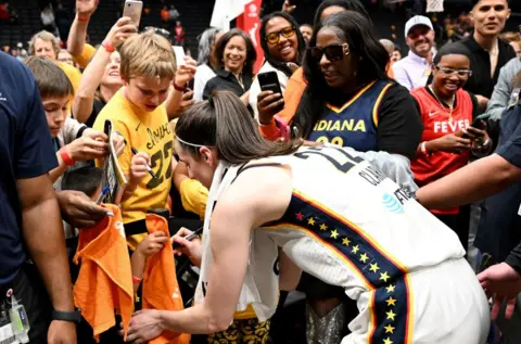 Getty Images Caitlin Clark signs fan jerseys after the Indiana Fever defeat the Mystics in Washington on Friday.