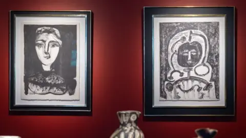 Castle Fine Art Two portraits, one of a woman and the other of a more abstract figure hung on a red gallery wall